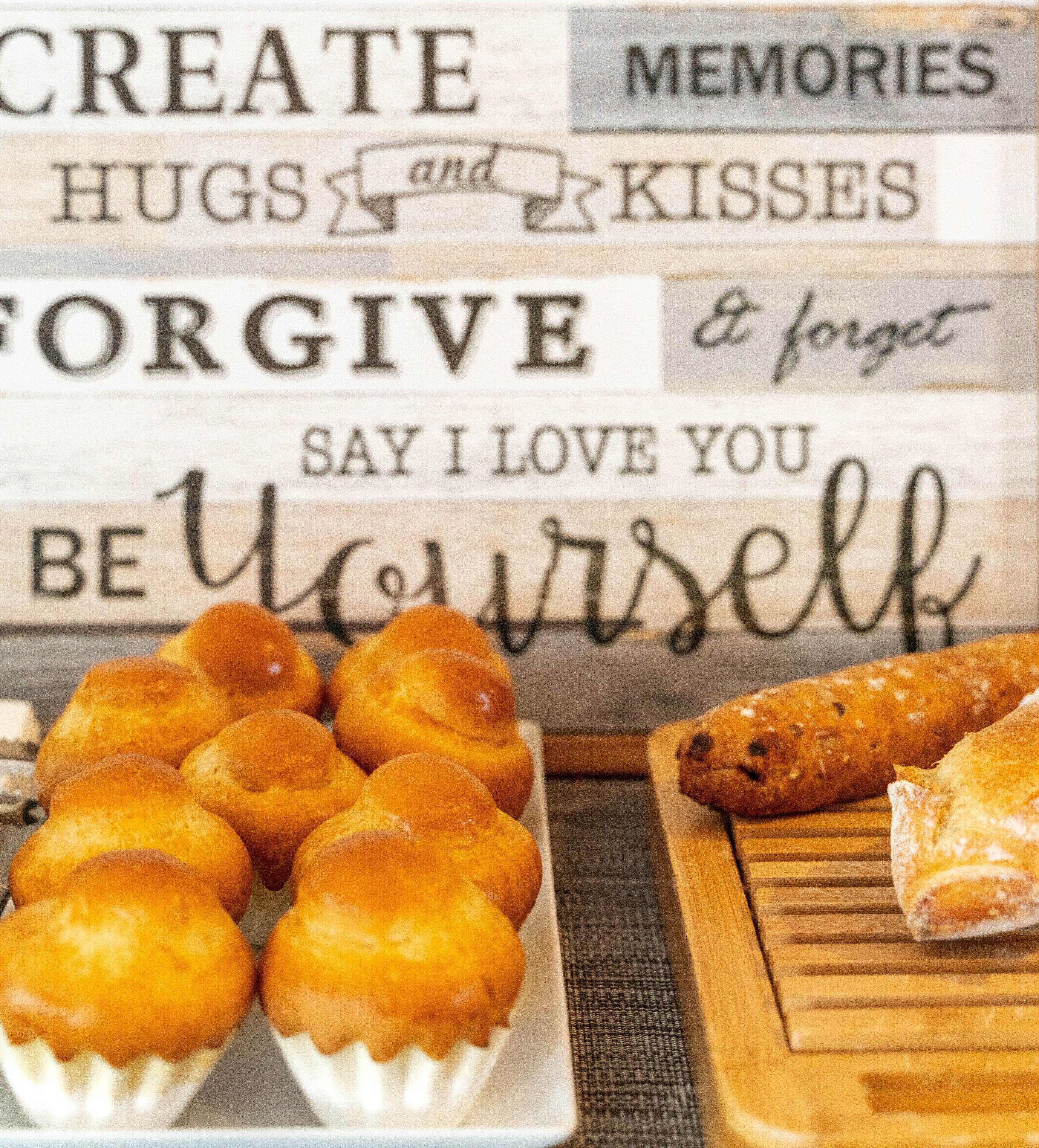 A wooden sign with phrases like "CREATE HUGS and KISSES," "FORGIVE," and "SAY I LOVE YOU BE YOURSELF."