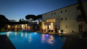 A swimming pool with lounge chairs and a building with multiple windows and balconies.