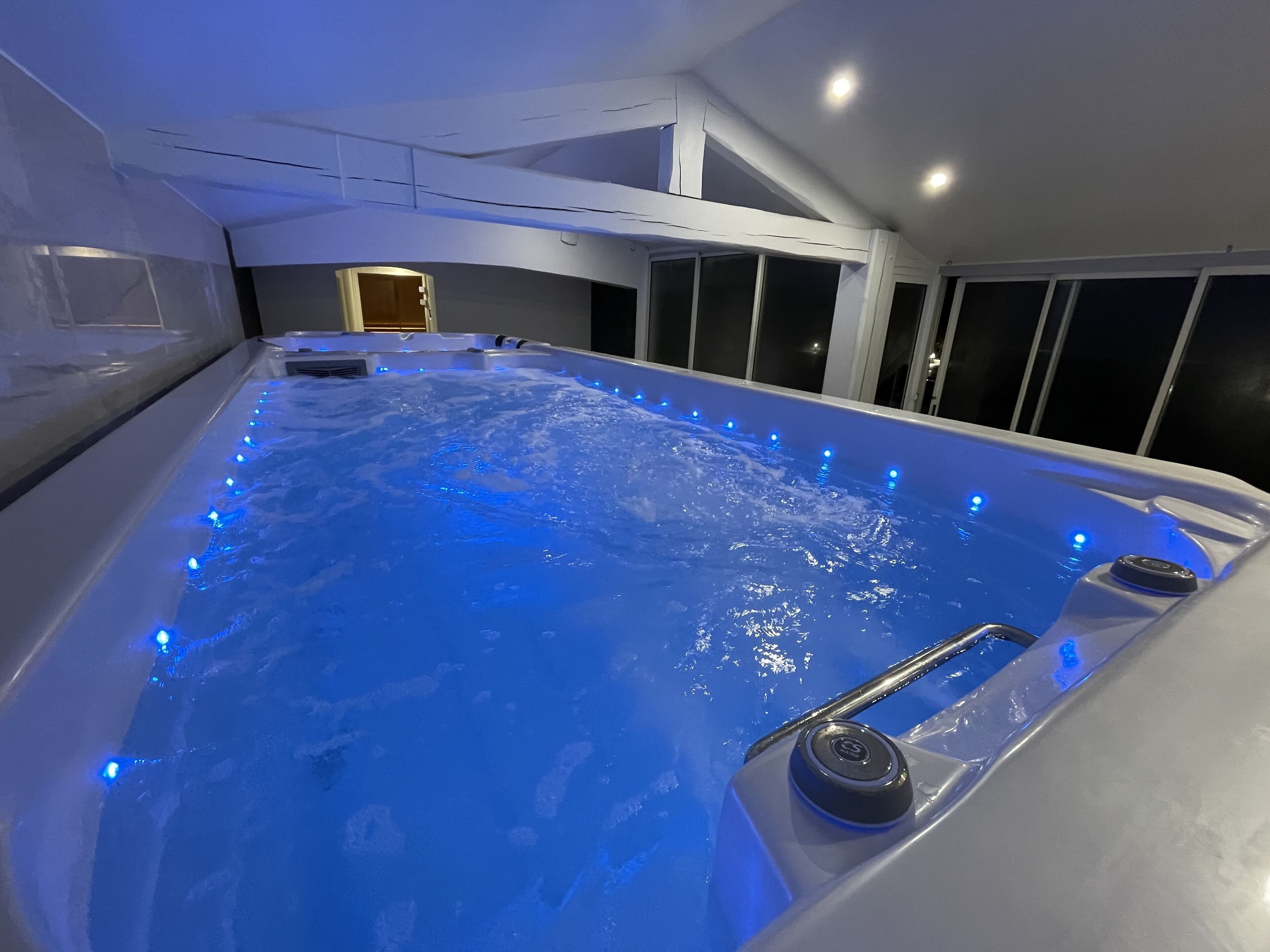 A hot tub with blue LED lights, a control panel, and a window in the background.