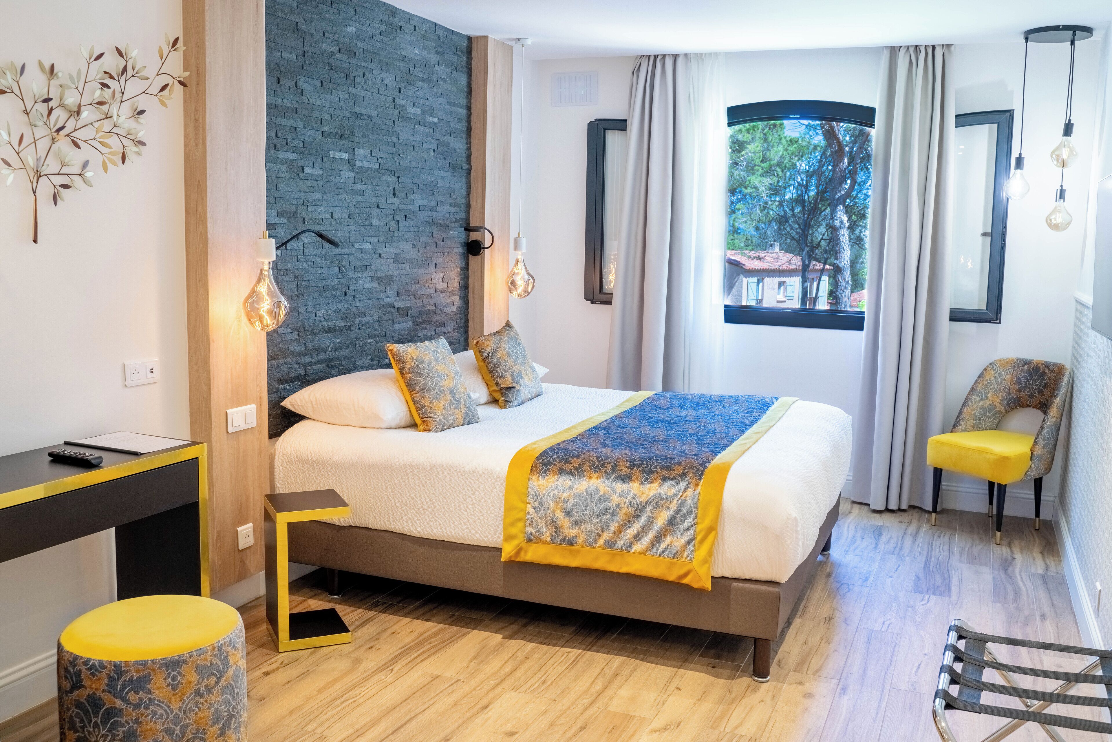 A modern bedroom with a bed, bedside table, chair, and a view of the outdoors.