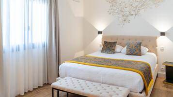 A neatly arranged bedroom with a bed, bench, and wall-mounted lights.