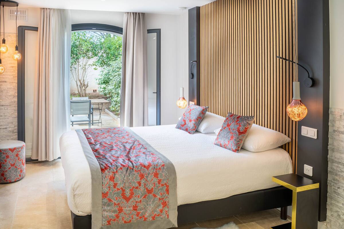 A modern bedroom with a large bed, a bedside table, and a view of an outdoor patio.