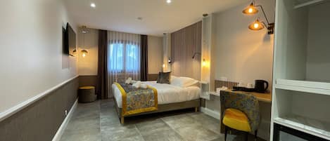 A hotel room with a bed, a desk, a chair, and a TV.