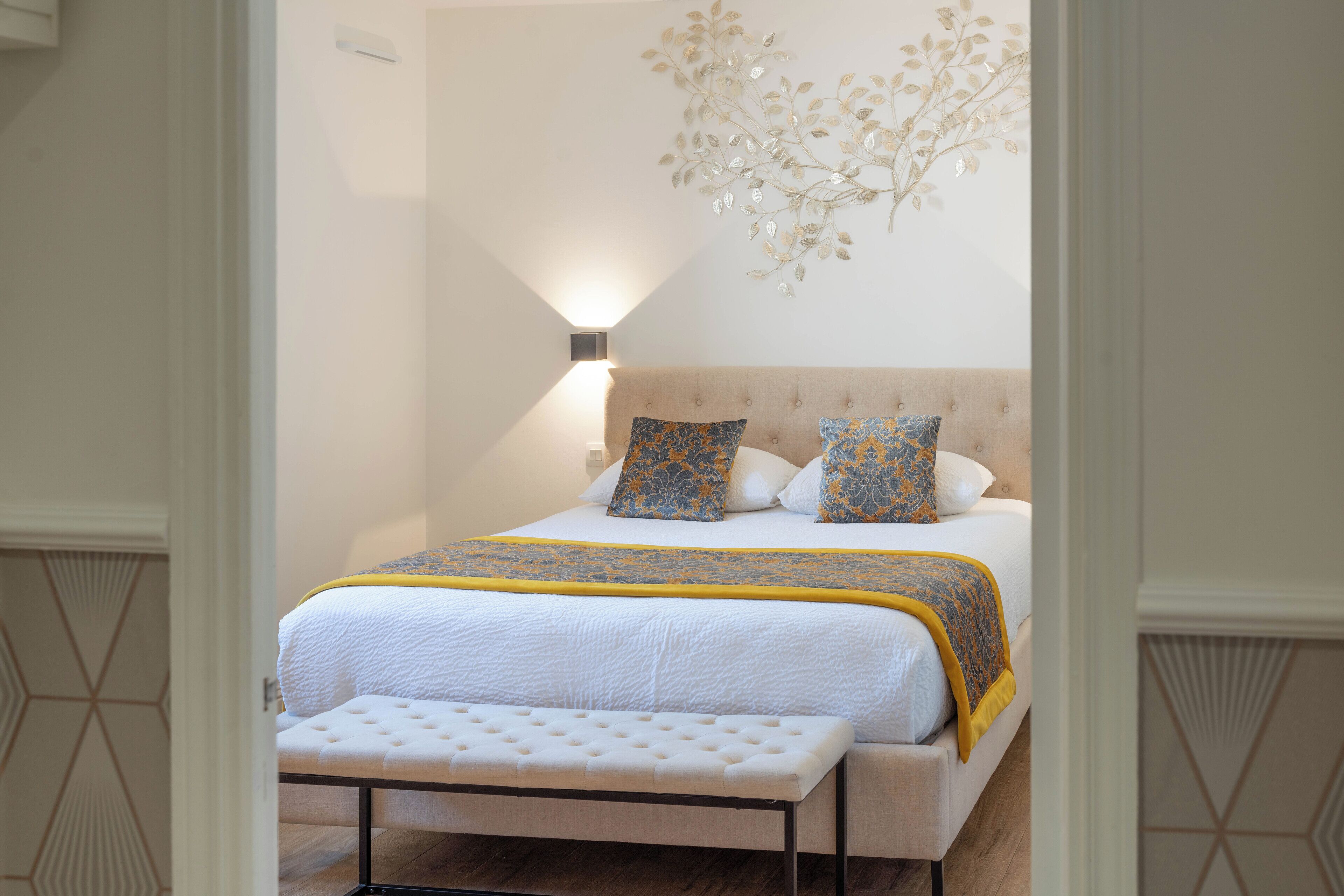 Un dormitorio ordenado con cama, banco y un adorno de pared.