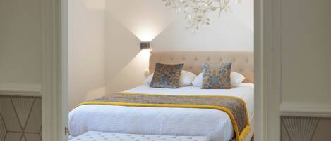 A neatly arranged bedroom with a bed, bench, and decorative wall piece.