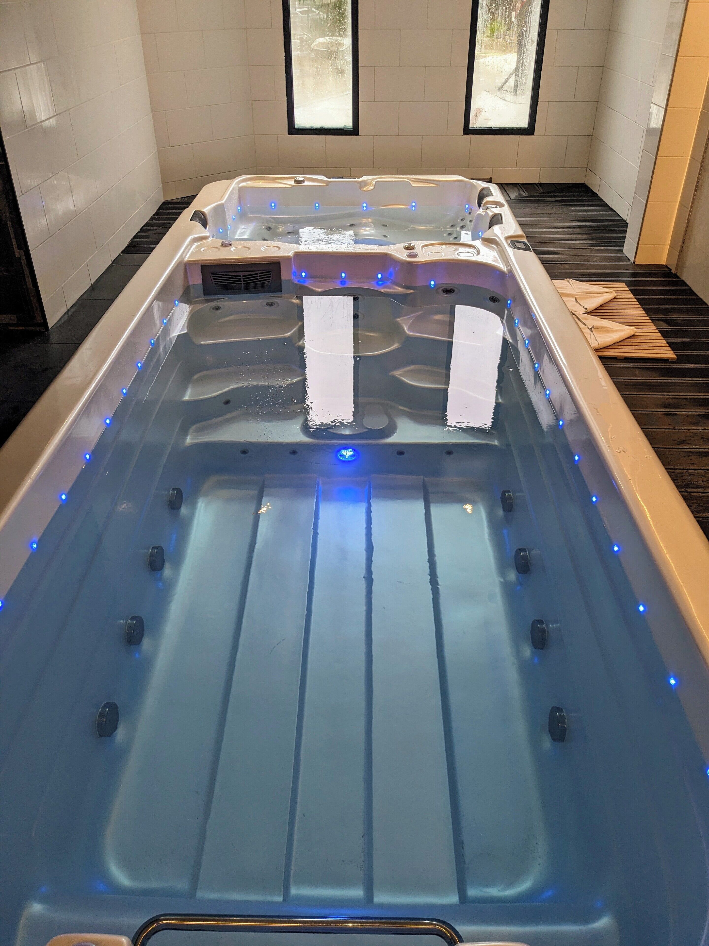 A hot tub with multiple jets, a wooden platform, and a tiled floor.