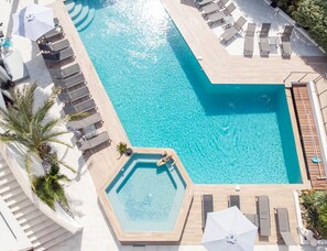 A large rectangular pool with clear blue water, surrounded by lounge chairs and umbrellas. - Confidentiel hôtel & Spa (Saint-Raphael)