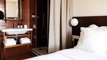 A hotel room with a bed, a bathroom with a sink, and a shower.