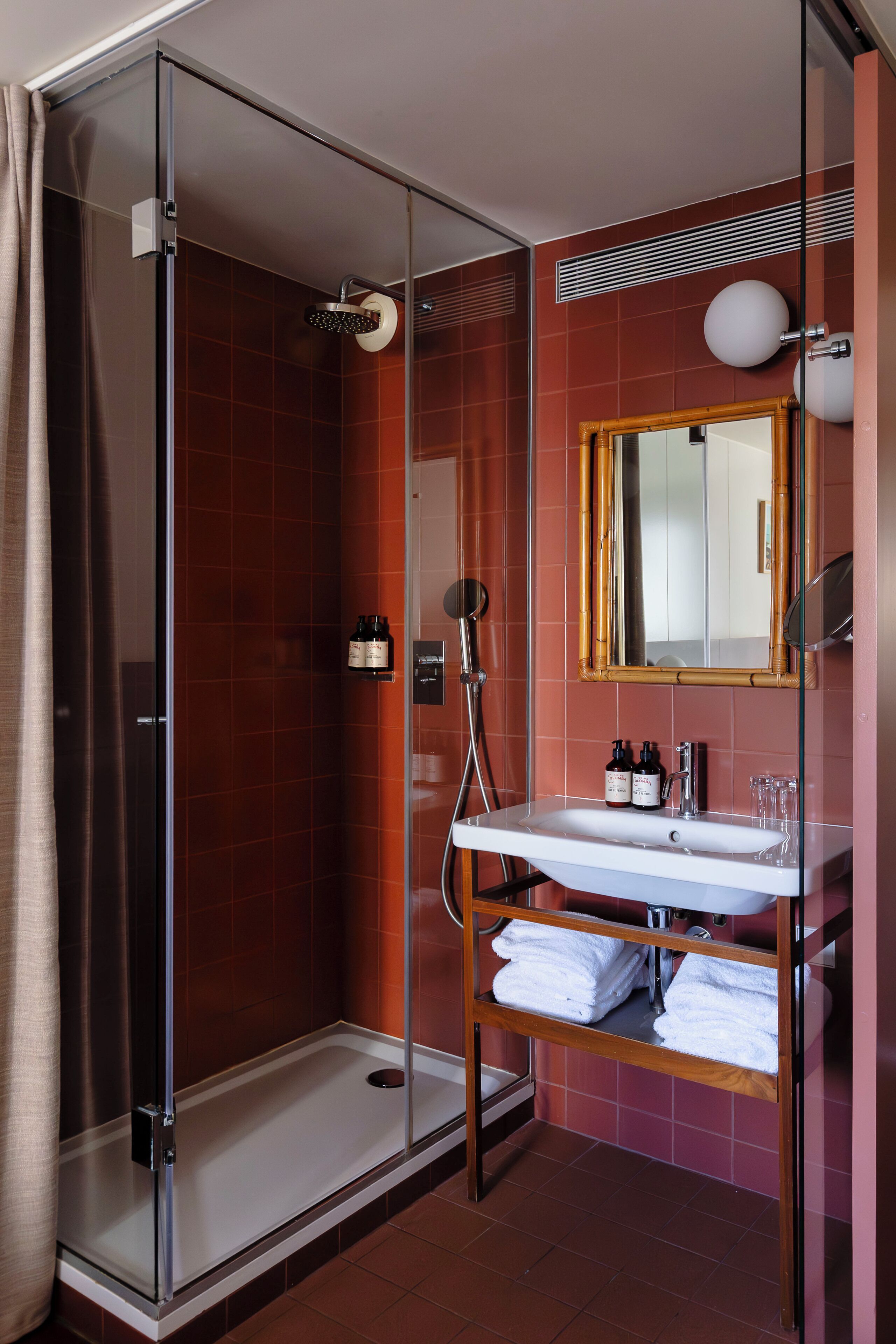 A modern bathroom with a glass-enclosed shower, a white sink, and a mirror with a wooden frame.