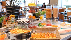 A buffet with various food items including waffles, pastries, fruits, and condiments.