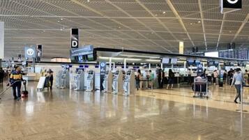 Una terminal aeroportuaria espaciosa con múltiples mostradores de registro y un suelo limpio y pulido.