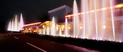 A building with multiple fountains and a well-lit exterior.
