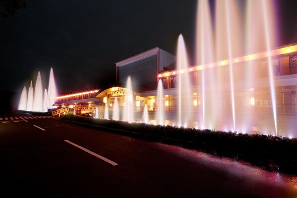 A building with multiple fountains and a well-lit exterior. - International Resort Hotel Yurakujo (Tomisato)