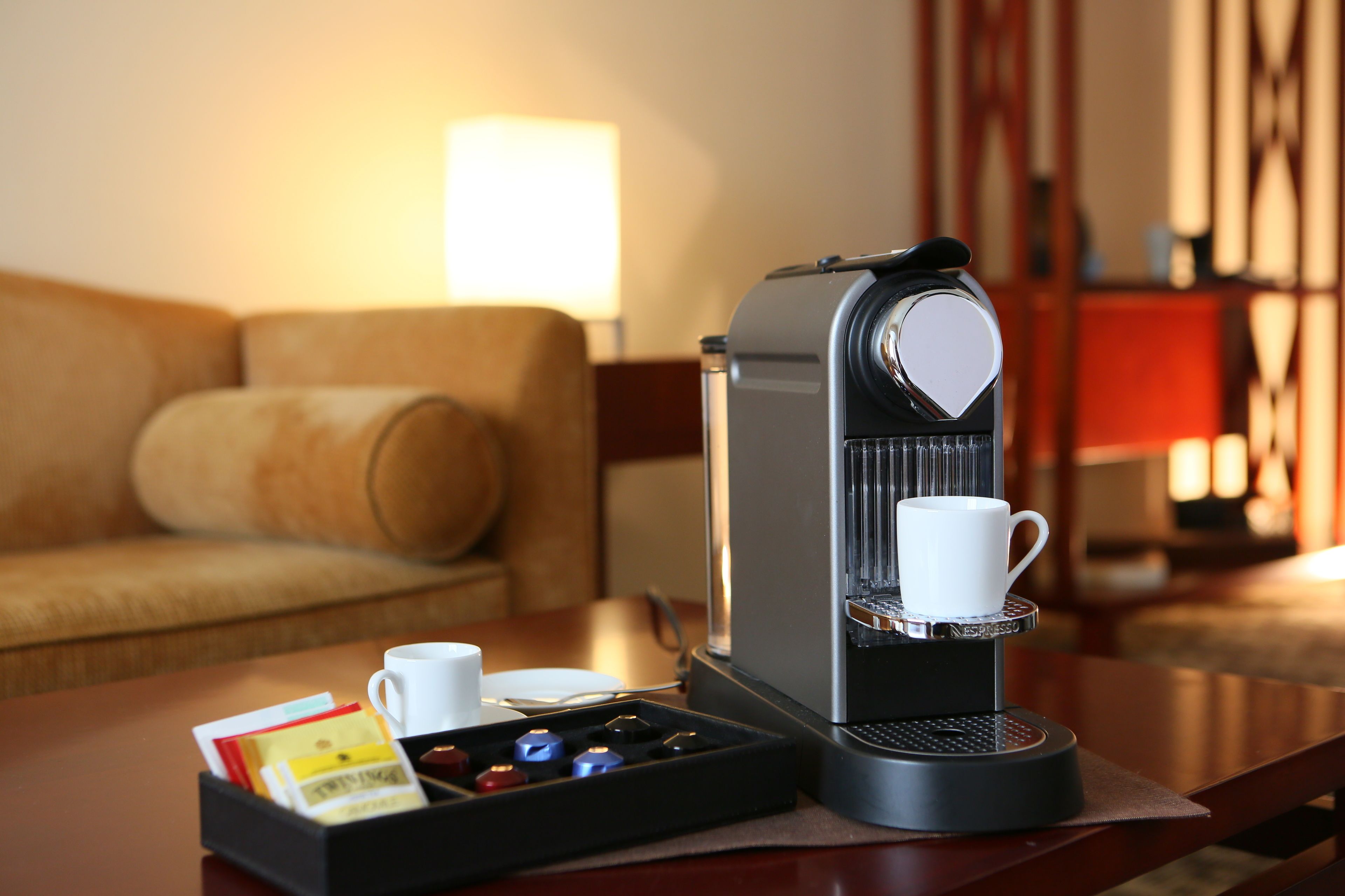 A coffee machine on a table with a cup and a tray of coffee pods.