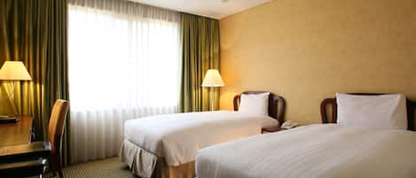 A hotel room with two beds, a desk, and a chair.