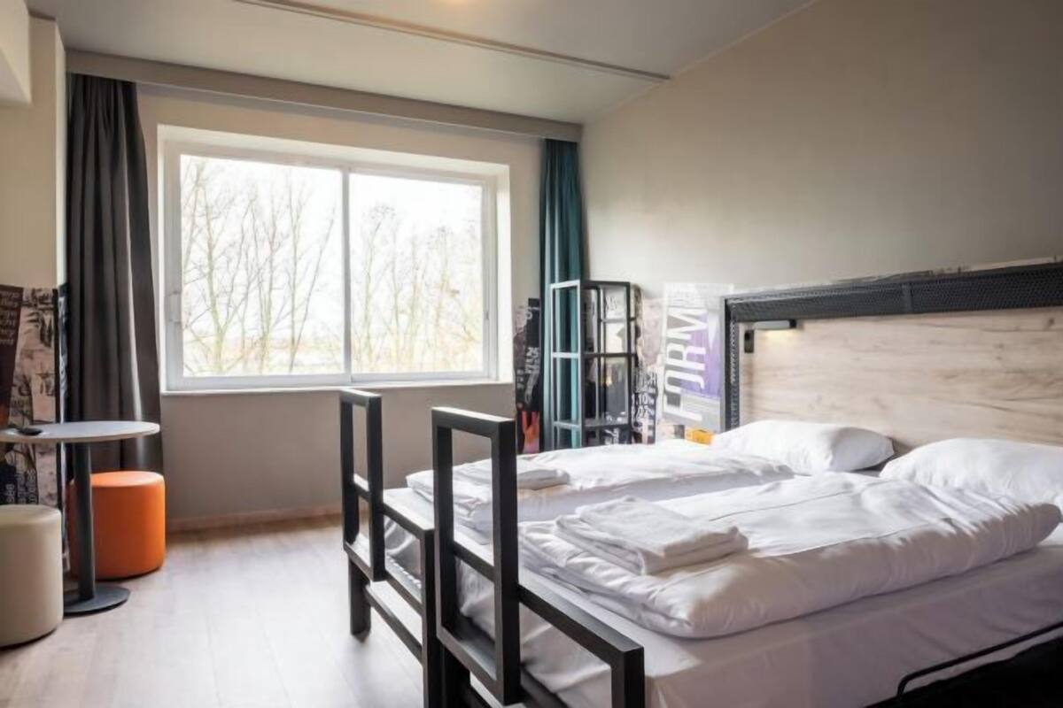 A bedroom with a bed, a window, a desk, and a chair.
