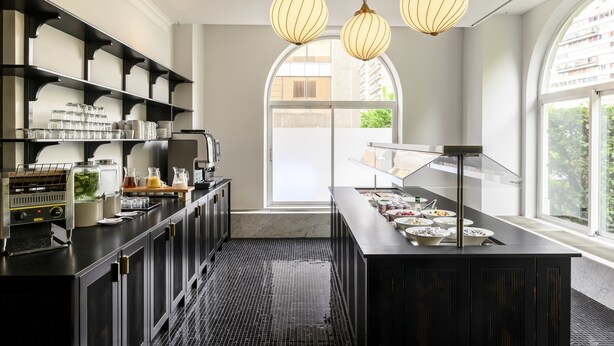 Una cocina moderna con encimeras negras, electrodomésticos de acero inoxidable y una vitrina de vidrio.