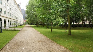 Een grindpad, begrensd door bomen en een gebouw met boogvensters.