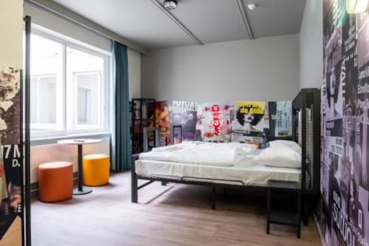 Un dormitorio con una cama, una ventana, un radiador y un cartel en la pared.
