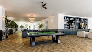 A pool table in a room with a herringbone floor, a ceiling fan, and a bookshelf. - a&o Brussel Centrum   (Brussels)