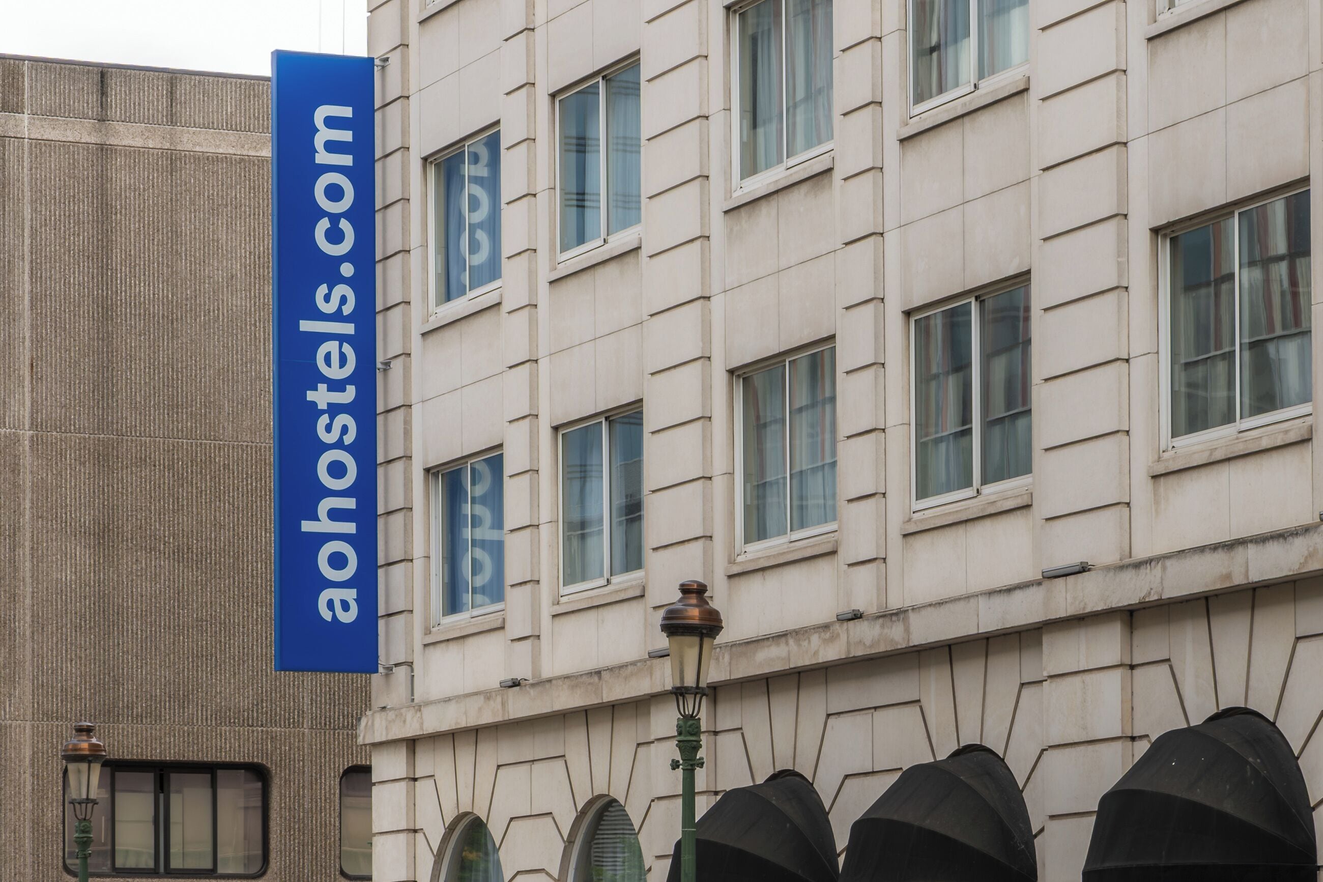 A building with a blue sign reading 'aohotels.com' and a lamp post.