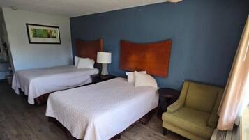 A hotel room with two beds, a sofa, a lamp, and a ceiling light fixture.
