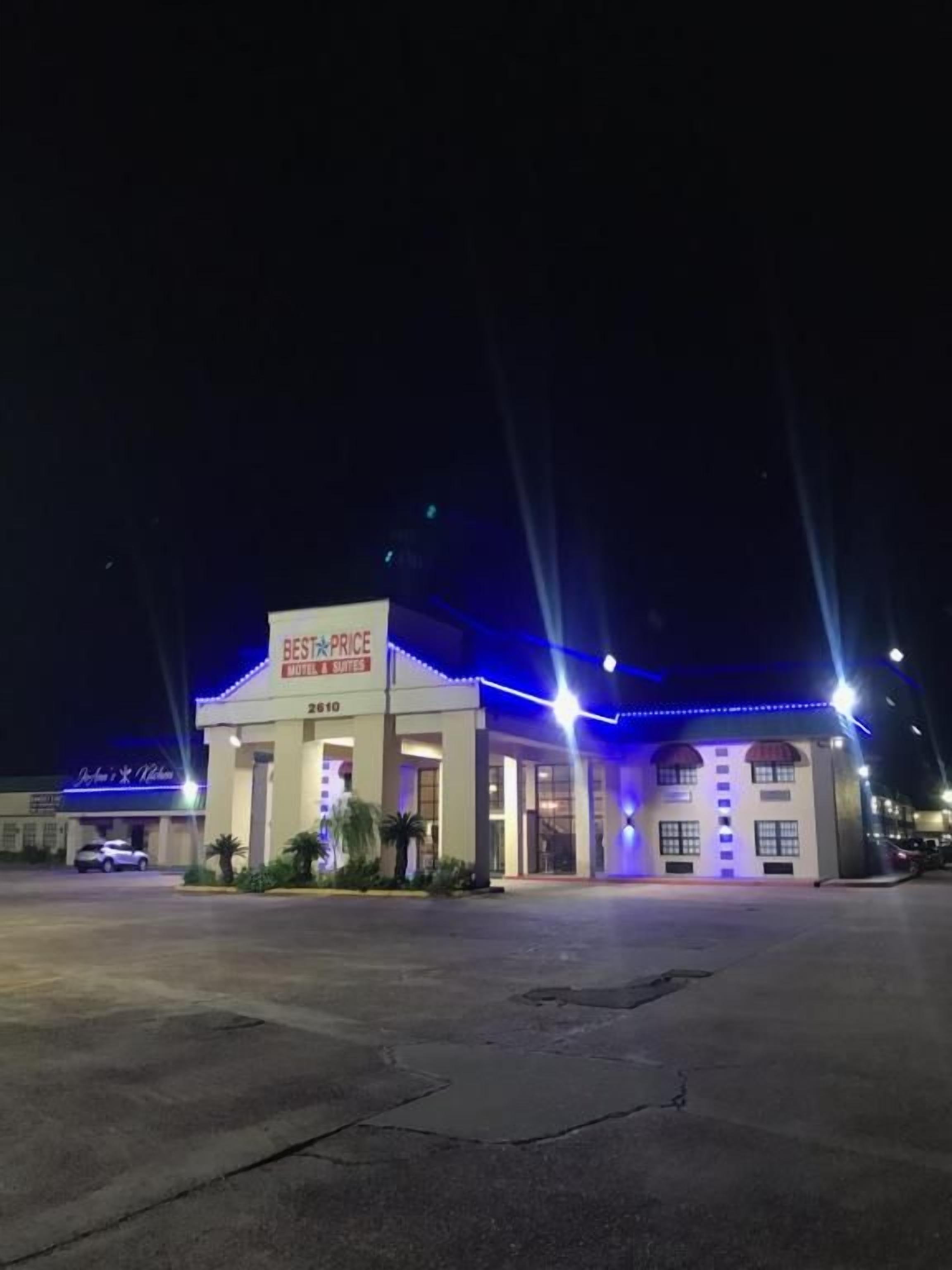 A building with a sign reading 'BEST PRICE HOTEL & SUITES' at night.