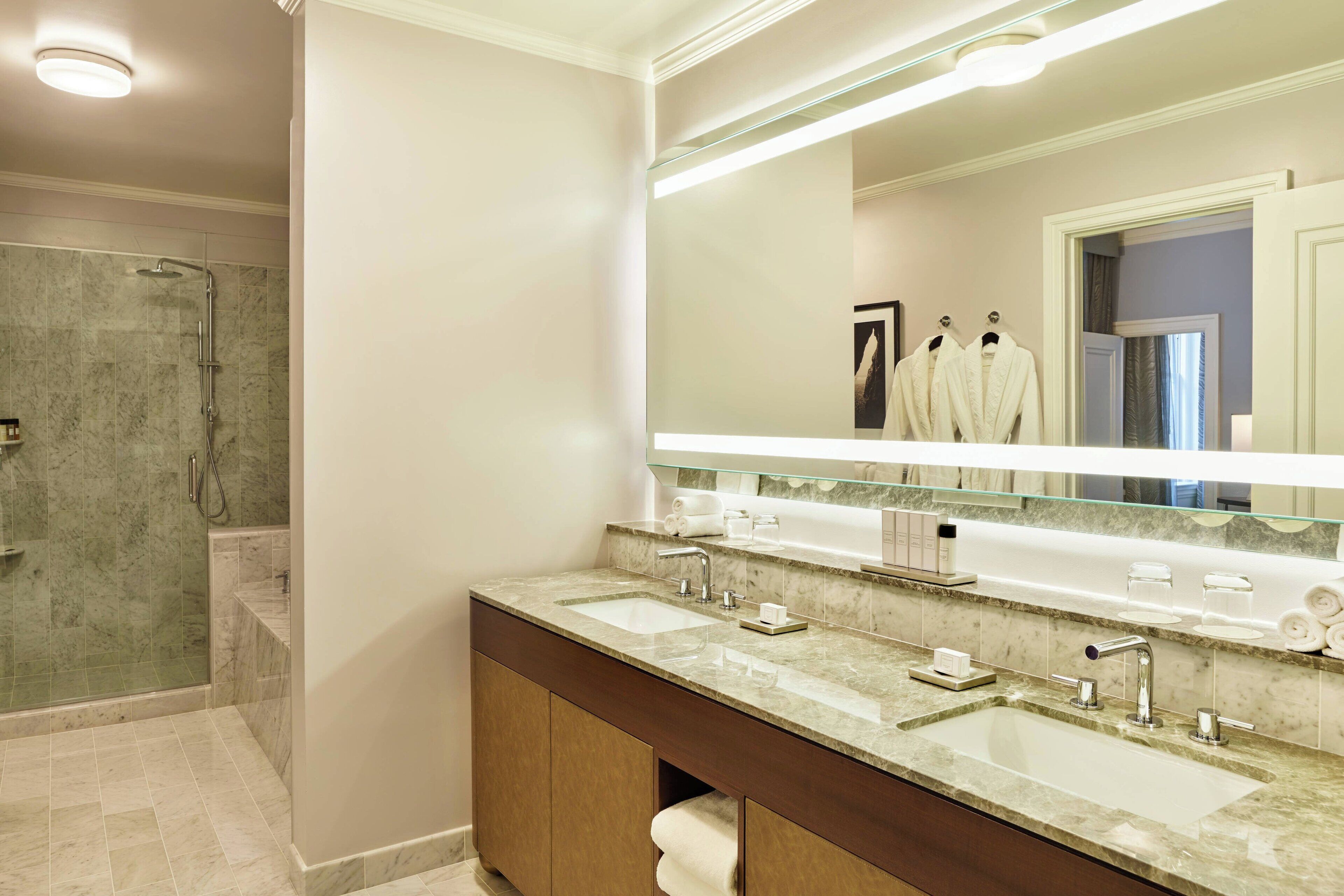 Une salle de bain moderne avec un grand miroir, deux lavabos et un espace douche.