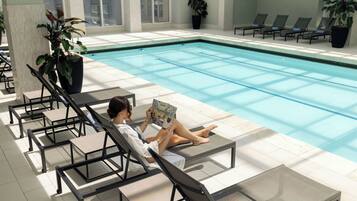 A poolside area with lounge chairs and a person reading a book.