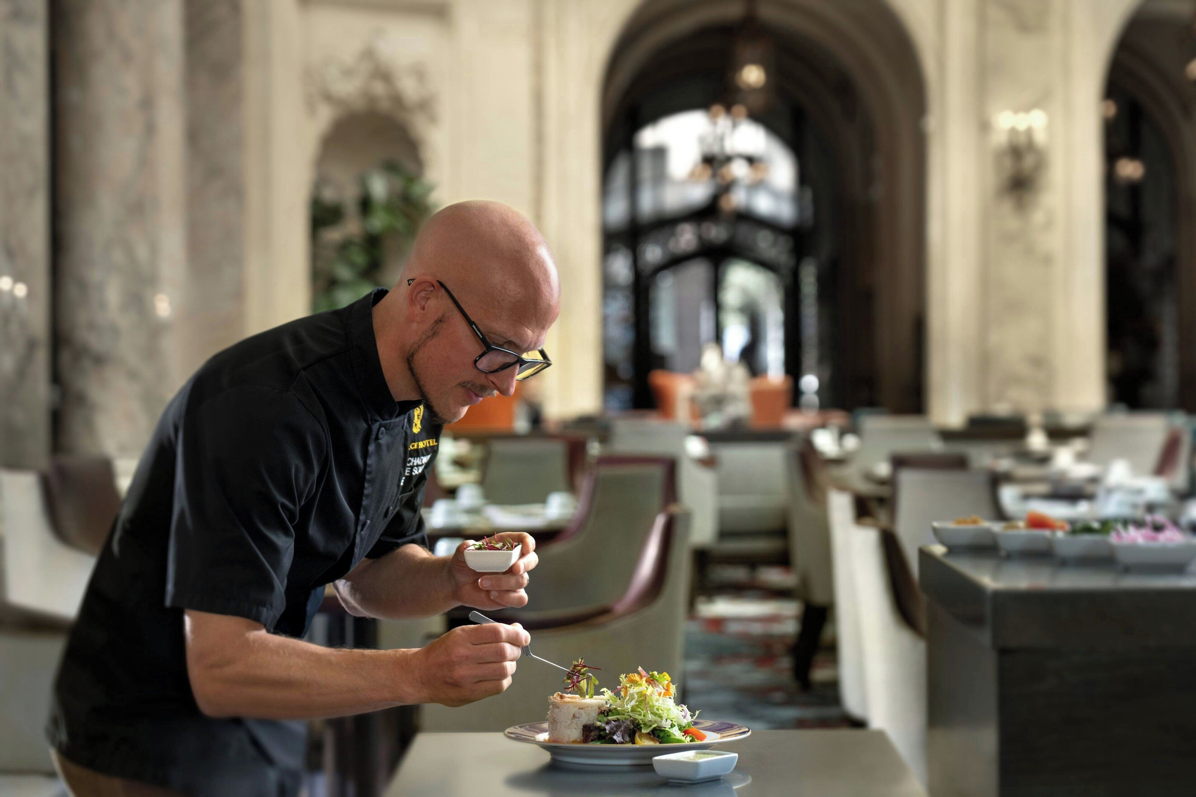 Un homme est assis à une table dans un restaurant dont l’intérieur est décoré de marbre et dont les plafonds sont en forme d’arc.