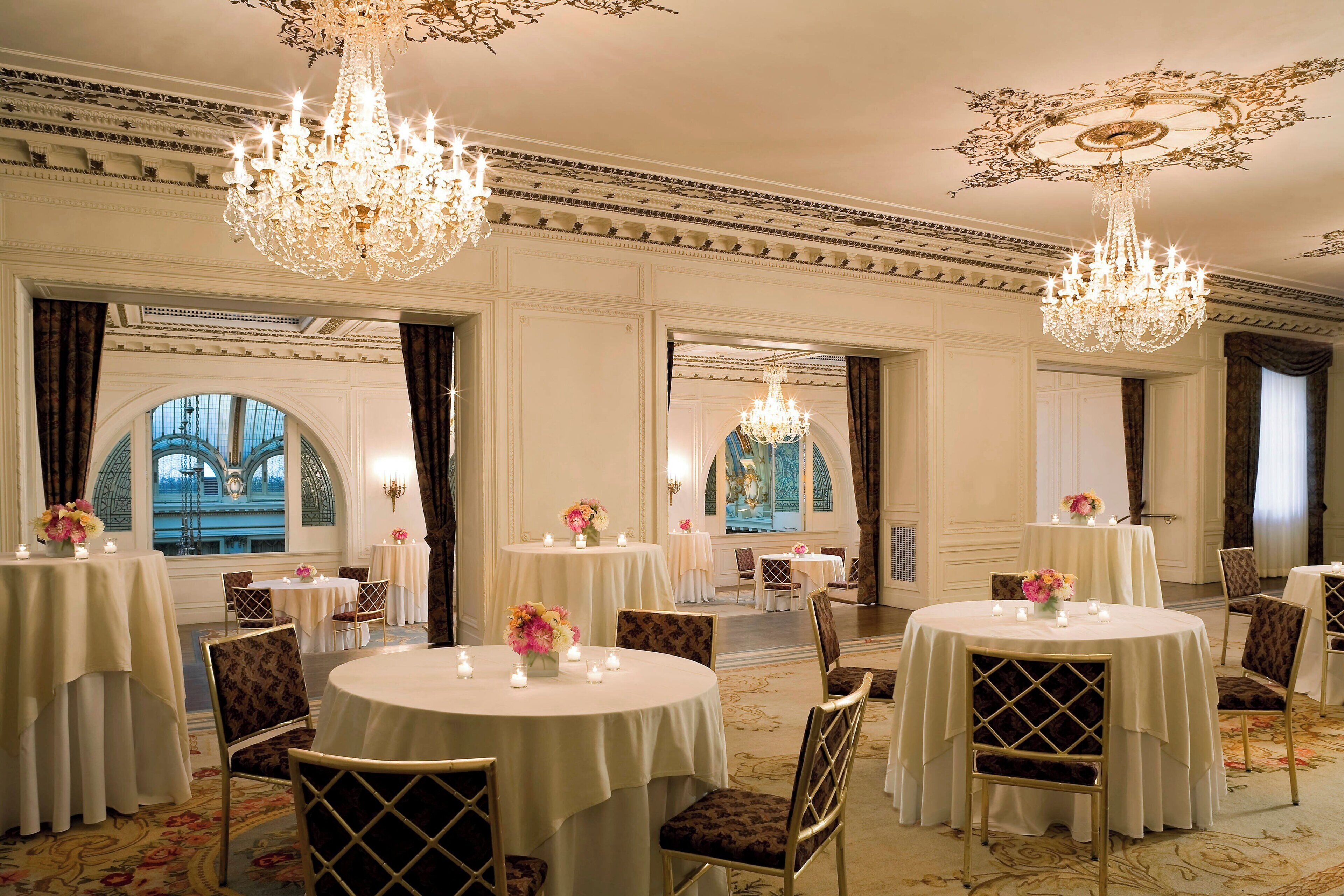 Une vaste salle à manger agrémentée de lustres somptueux, de tables rondes et d’élégantes chaises.