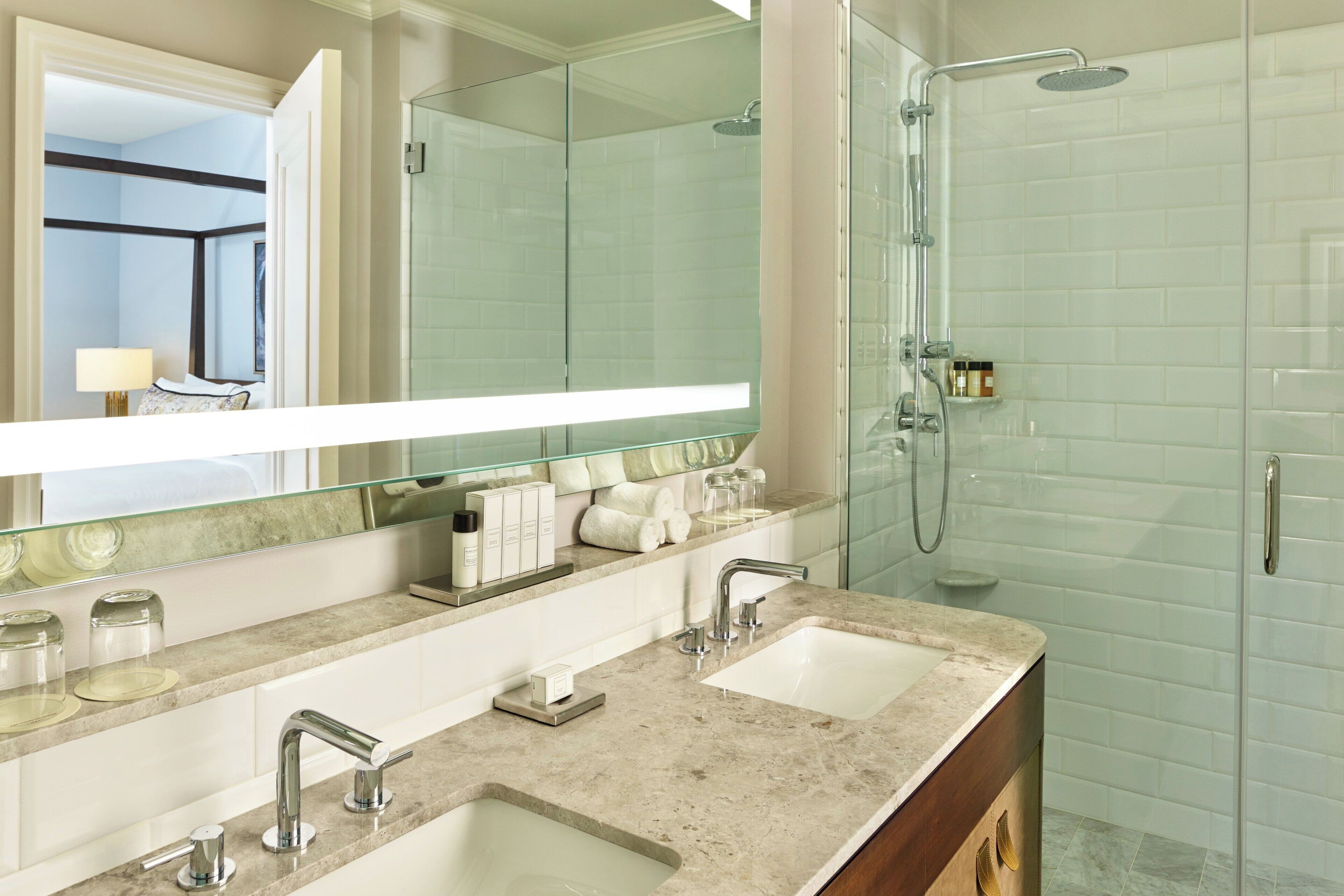 A modern bathroom with two sinks, a glass shower enclosure, and a large mirror.