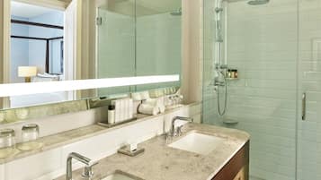 A modern bathroom with two sinks, a glass shower enclosure, and a large mirror.