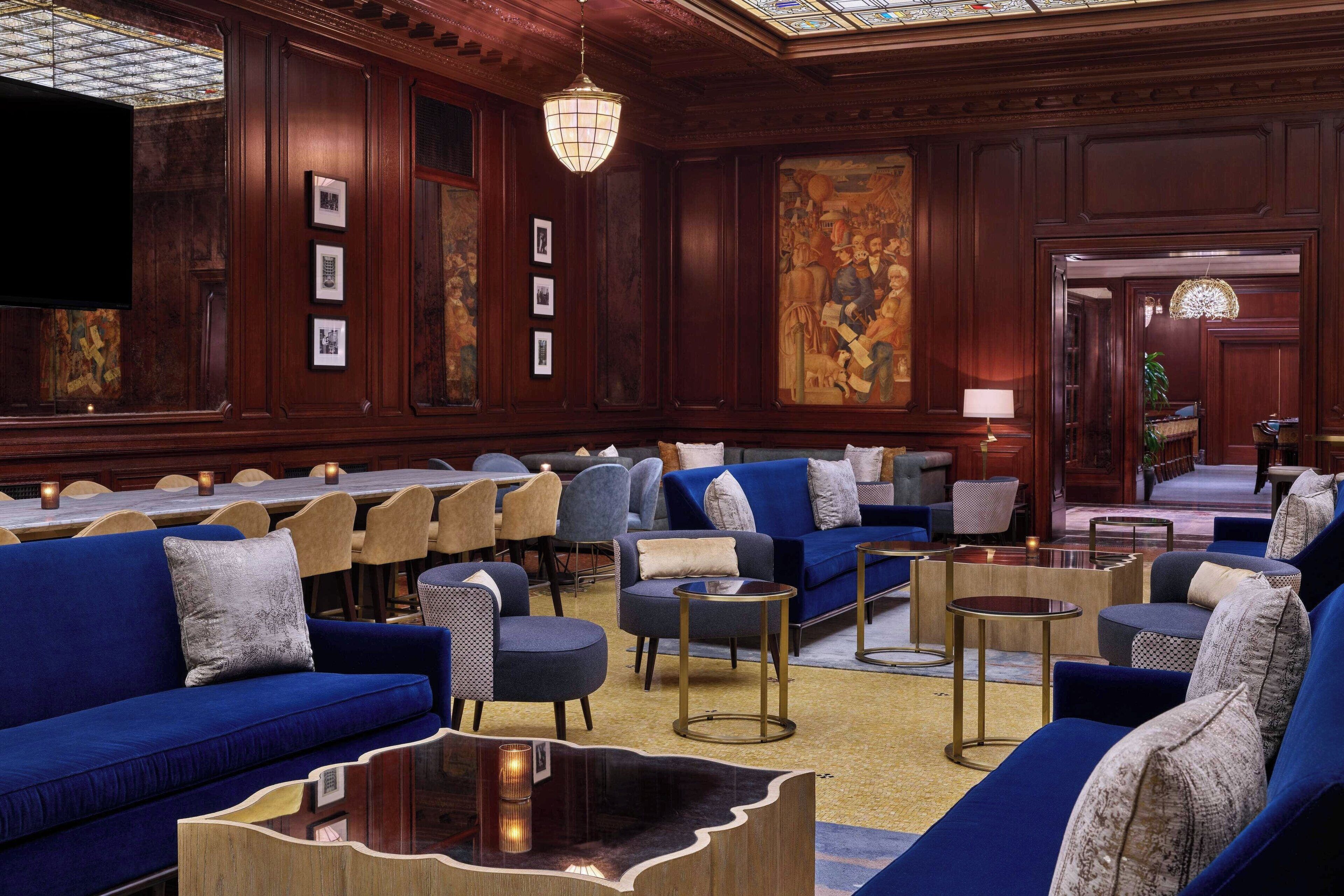 Eine großzügige Lobby mit mehreren Sitzbereichen, darunter Sofas und Sessel, die um einen zentralen Couchtisch angeordnet sind.