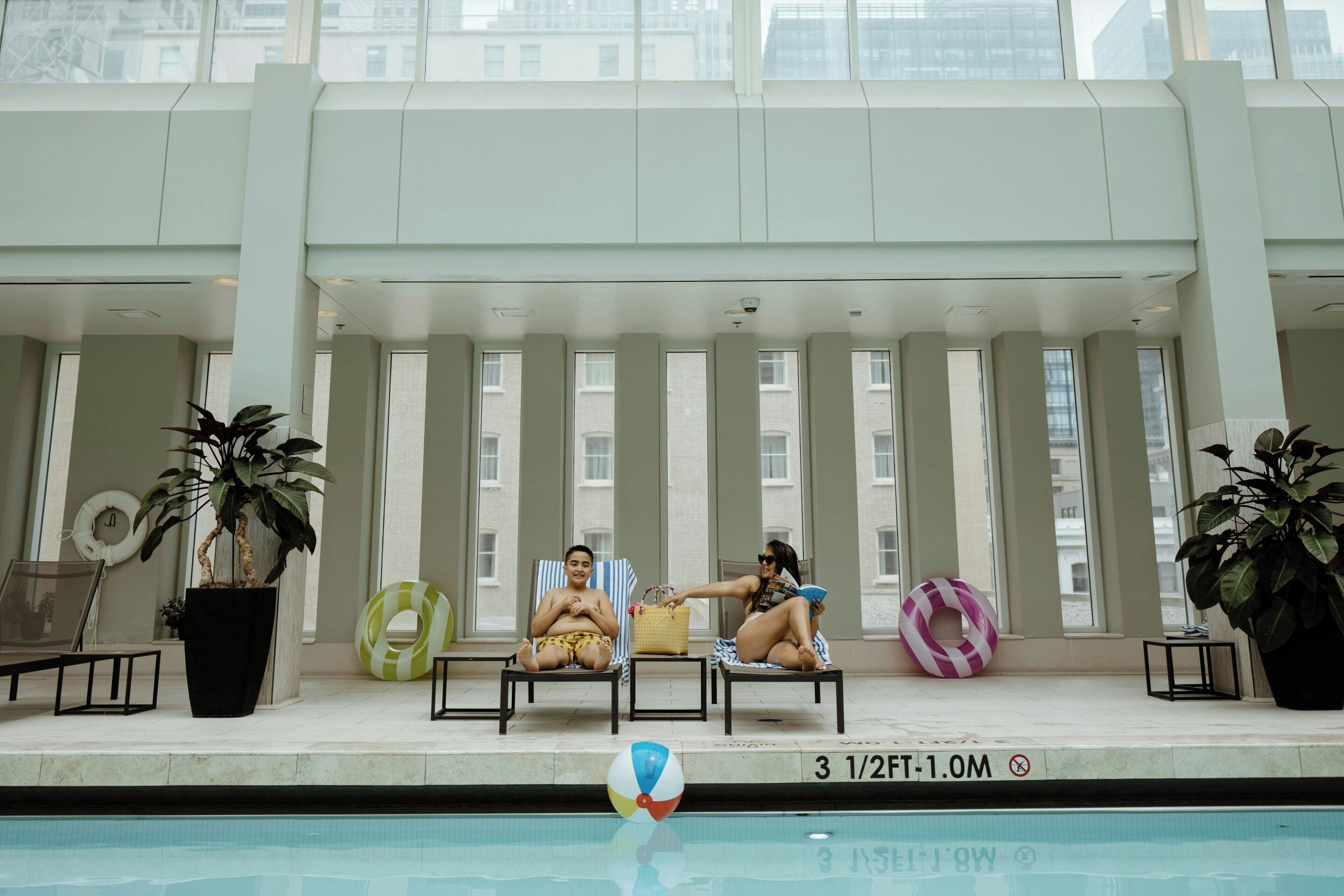 A pool area with two lounge chairs, a lifebuoy, and a pool sign indicating depth.