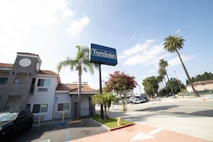 Un hotel Travelodge con aparcamiento, palmeras y cielo despejado.