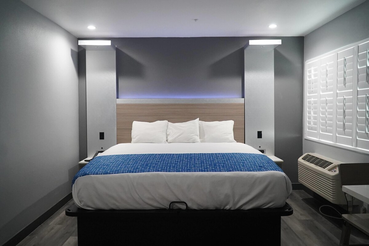 Une chambre d’hôtel moderne avec un grand lit, un bureau et une fenêtre équipée de stores.