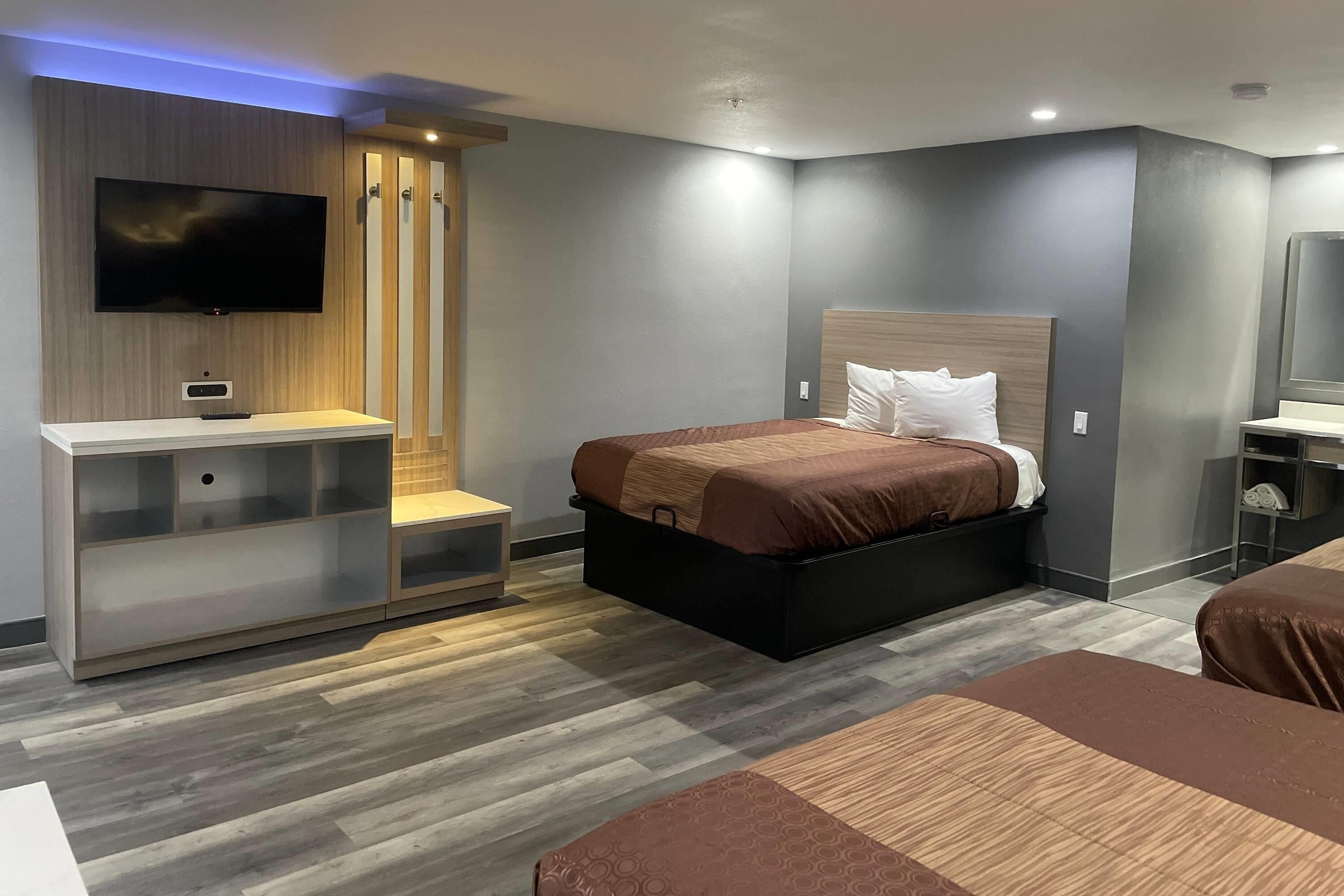 A modern hotel room with a bed, a TV, a desk, and a wardrobe.