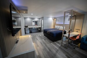 A modern hotel room with a bed, desk, chair, and a TV.