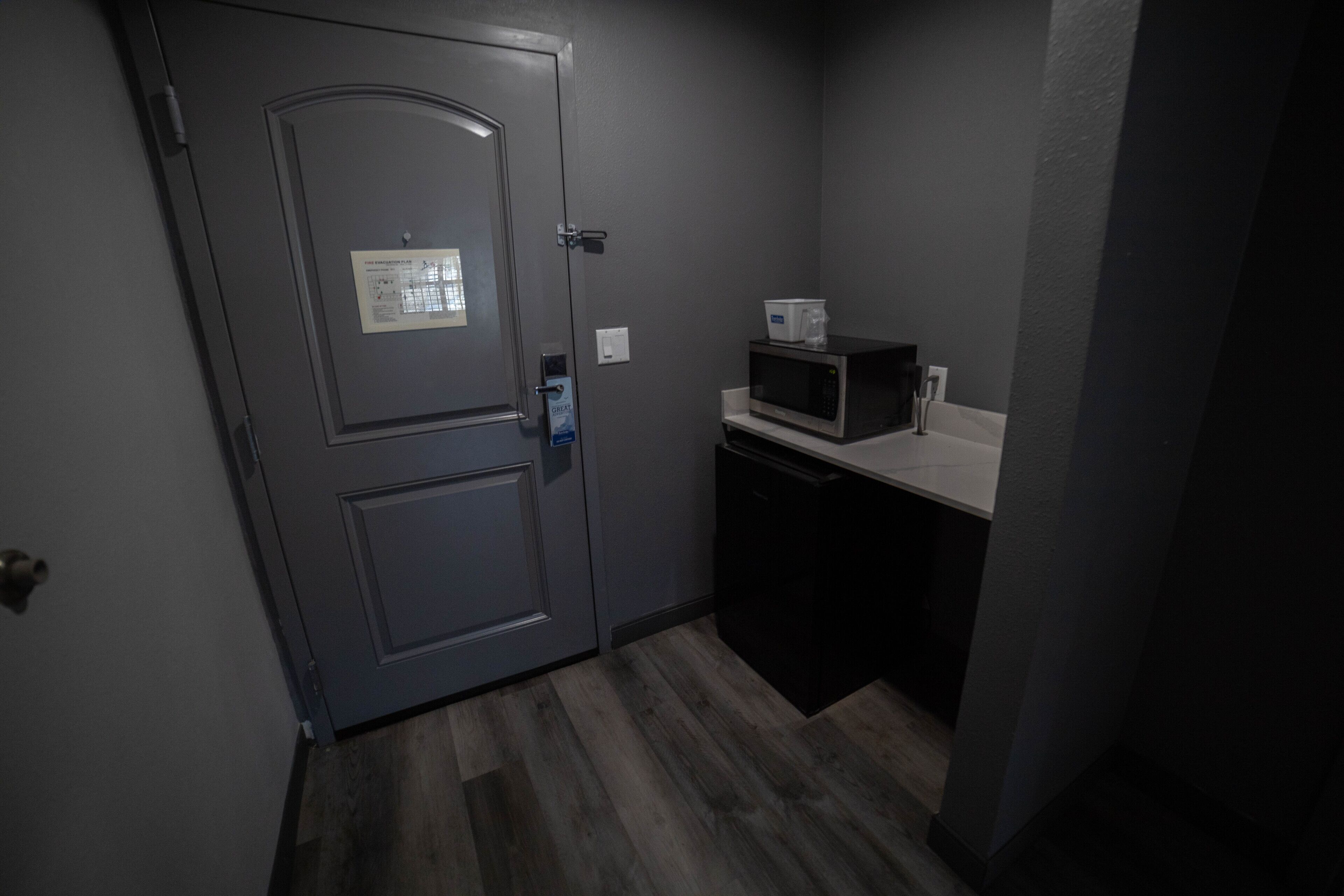 A small kitchenette with a microwave, a coffee maker, and a door with a security card reader.
