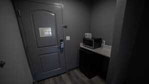 A small kitchenette with a microwave, a coffee maker, and a door with a security card reader. - Travelodge by Wyndham Whittier (Whittier)