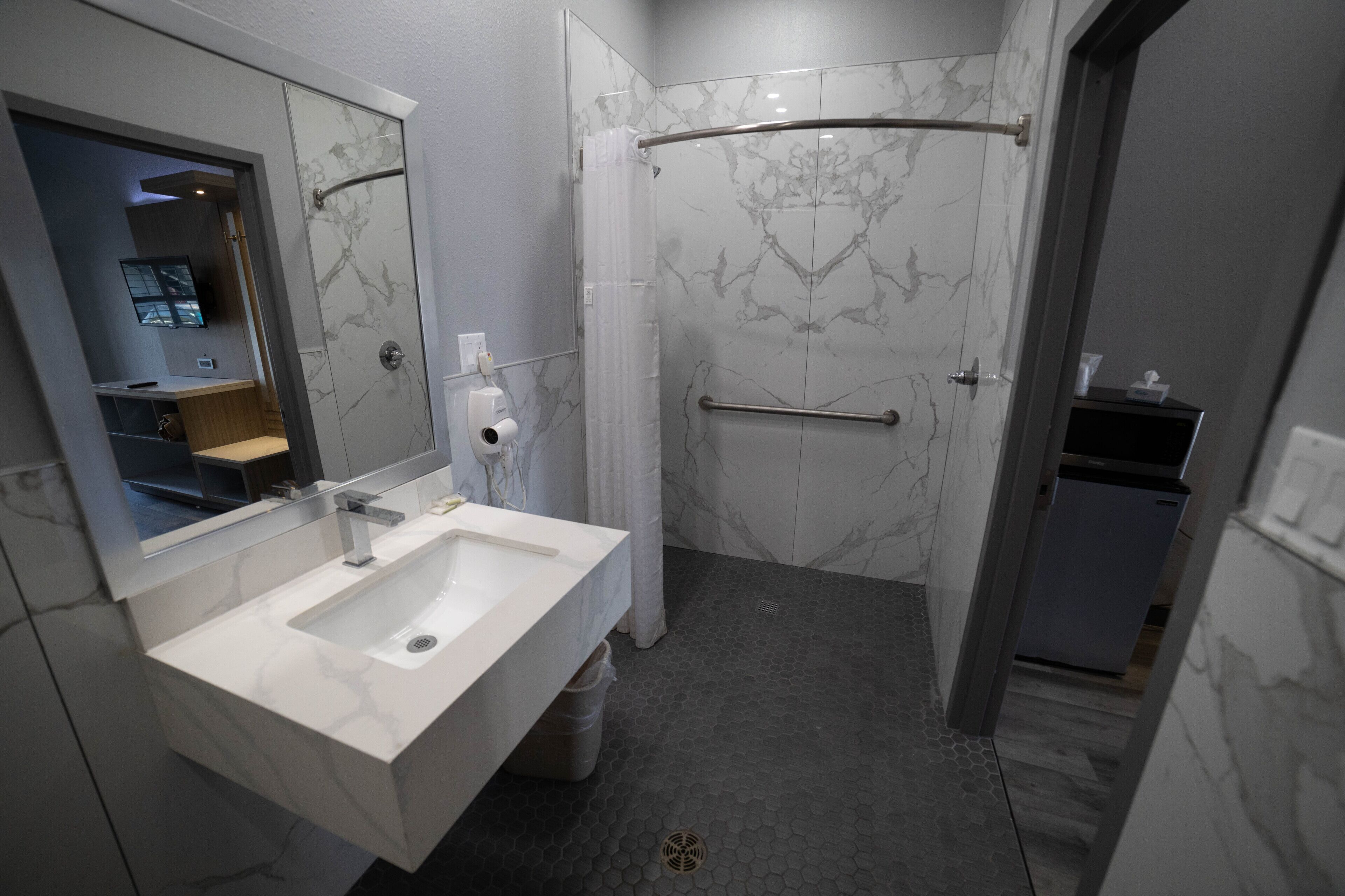 A modern bathroom with a marble sink, a shower with a glass door, and a visible toilet.