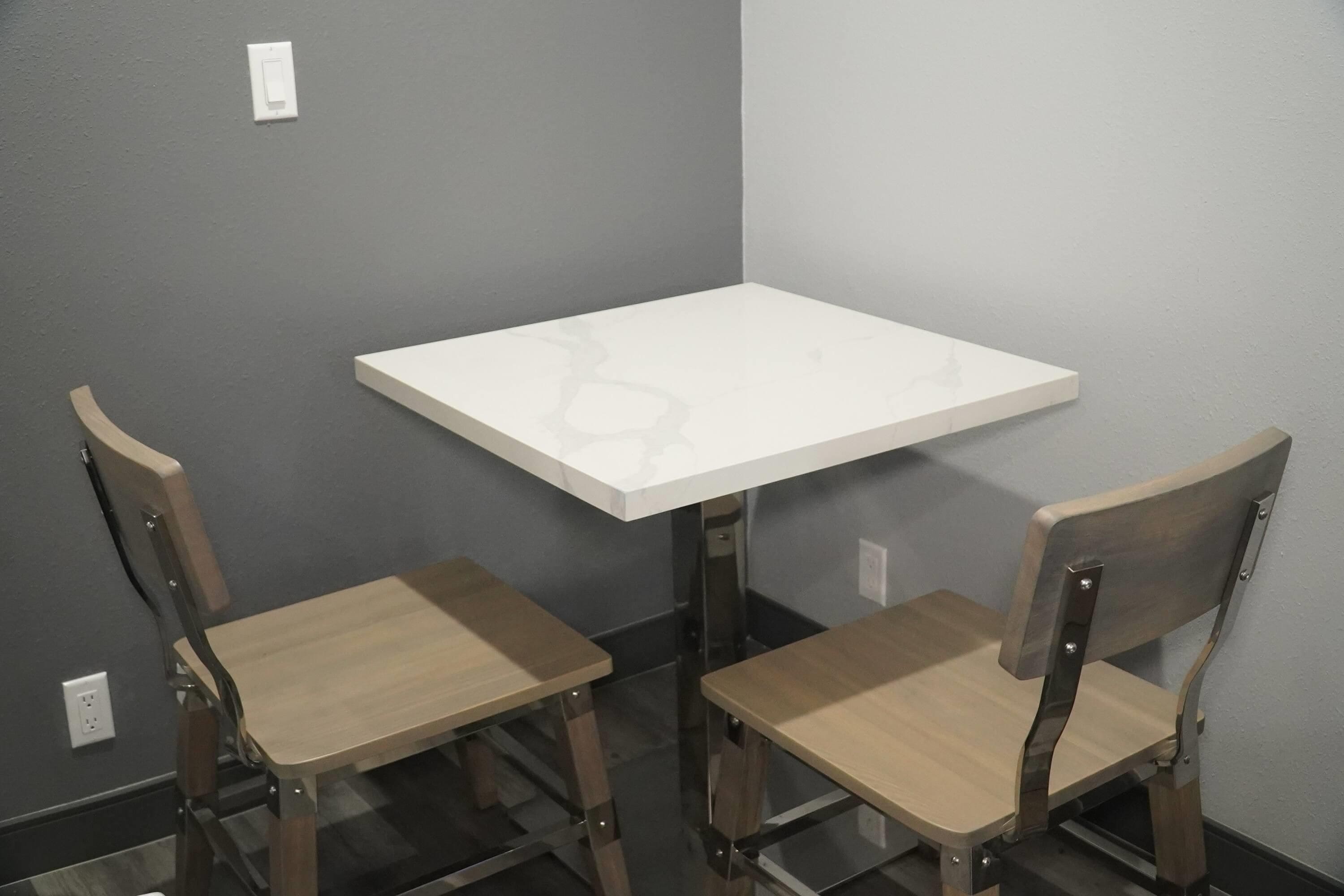 Una habitación pequeña con una mesa blanca y dos sillas de madera.