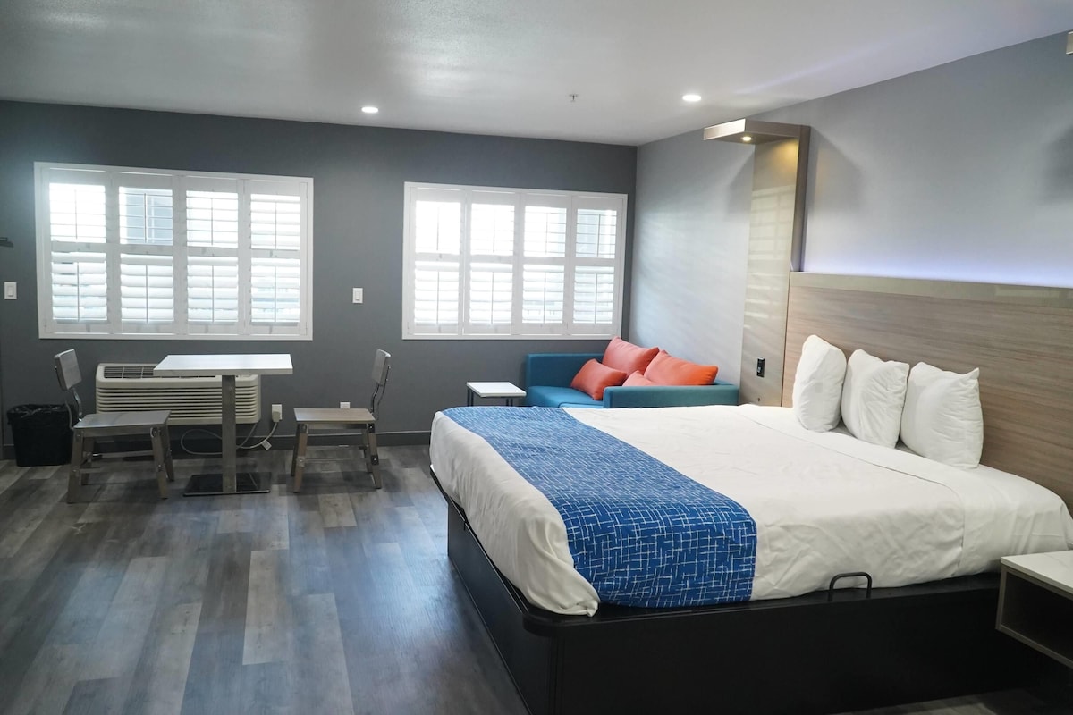 Une chambre d’hôtel avec un lit, un bureau, une chaise et une fenêtre.