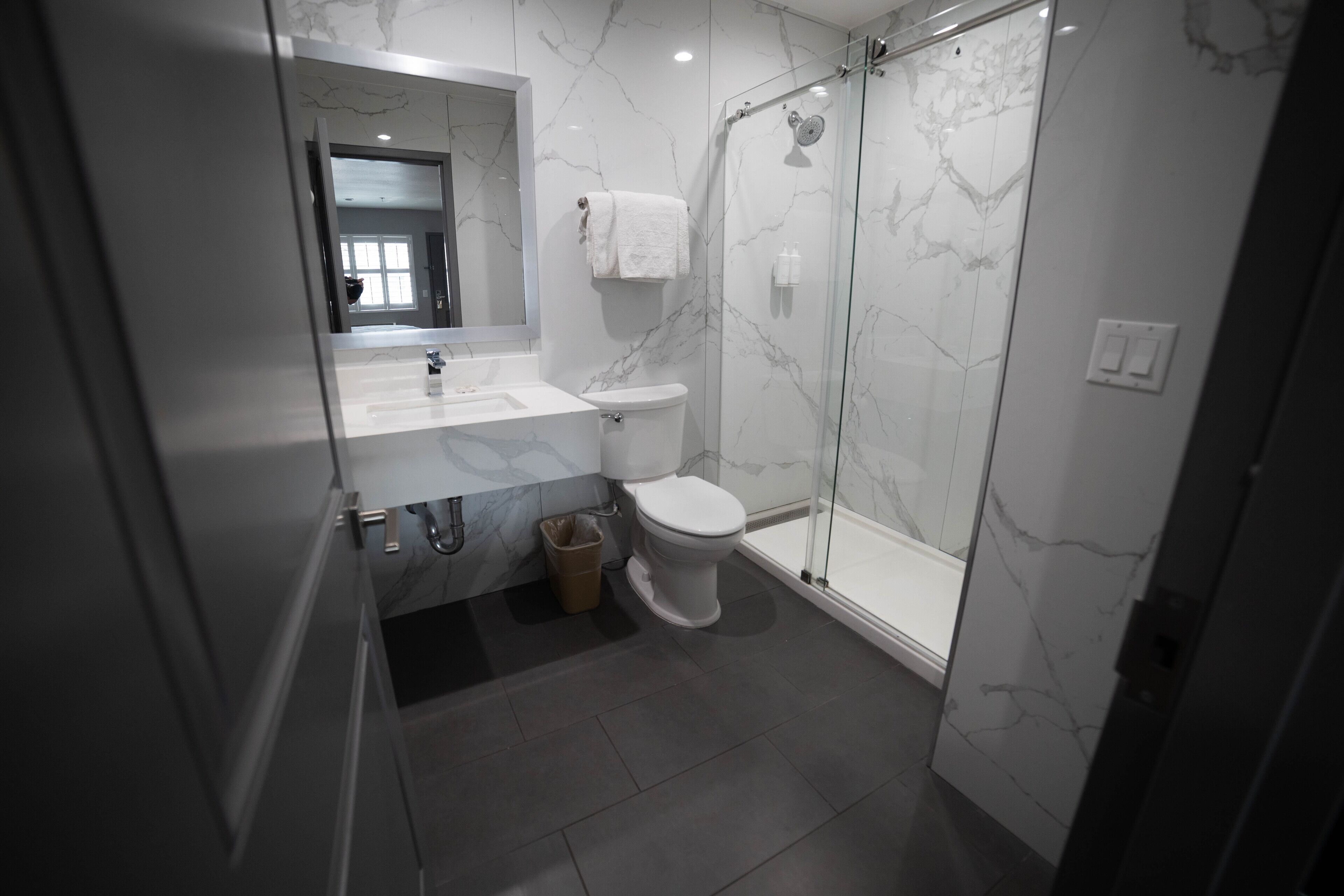 A modern bathroom with a glass-enclosed shower, a white toilet, and a marble-tiled vanity.
