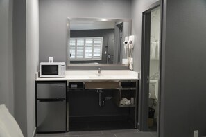 Een kleine badkamer met een ingebouwde magnetron, wastafel en toilet.