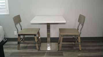 Una habitación pequeña con una mesa blanca y dos sillas.