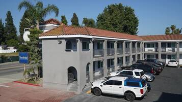 A Travelodge hotel with a parking lot, multiple cars, and surrounding greenery.