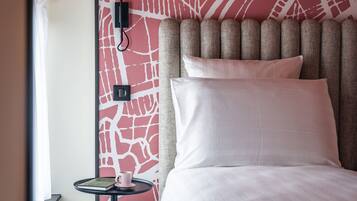A hotel room with a bed, a bedside table with a lamp, and a wall with a red abstract design.