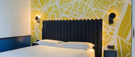 Una habitación de hotel moderna con una cama grande, diseño de pared con vista a la ciudad y dos lámparas fijadas a la pared.